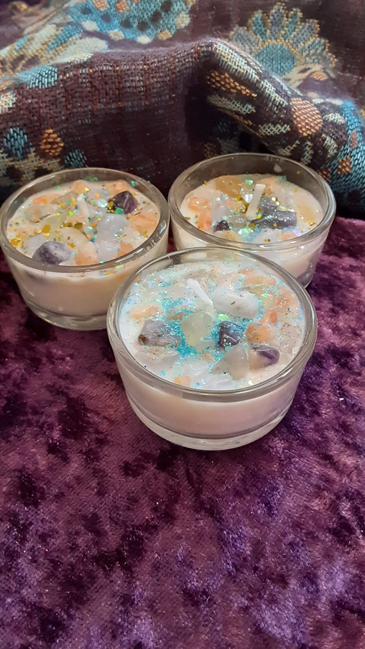 Three candles are sitting on a purple table.