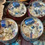 A group of four candles with different colored stones.