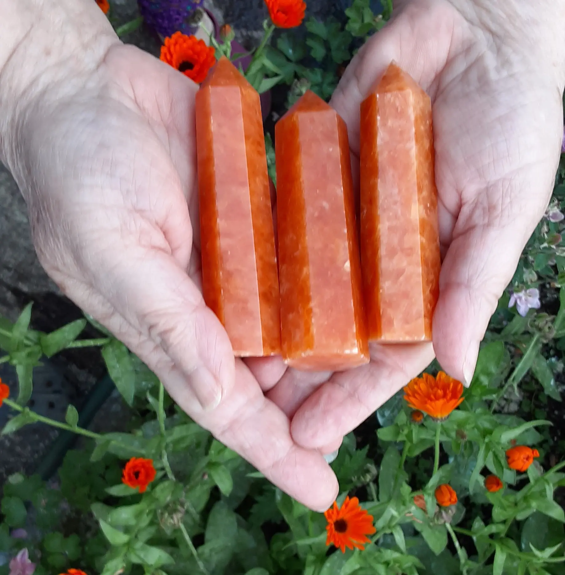 Hands holding three orange crystal towers.