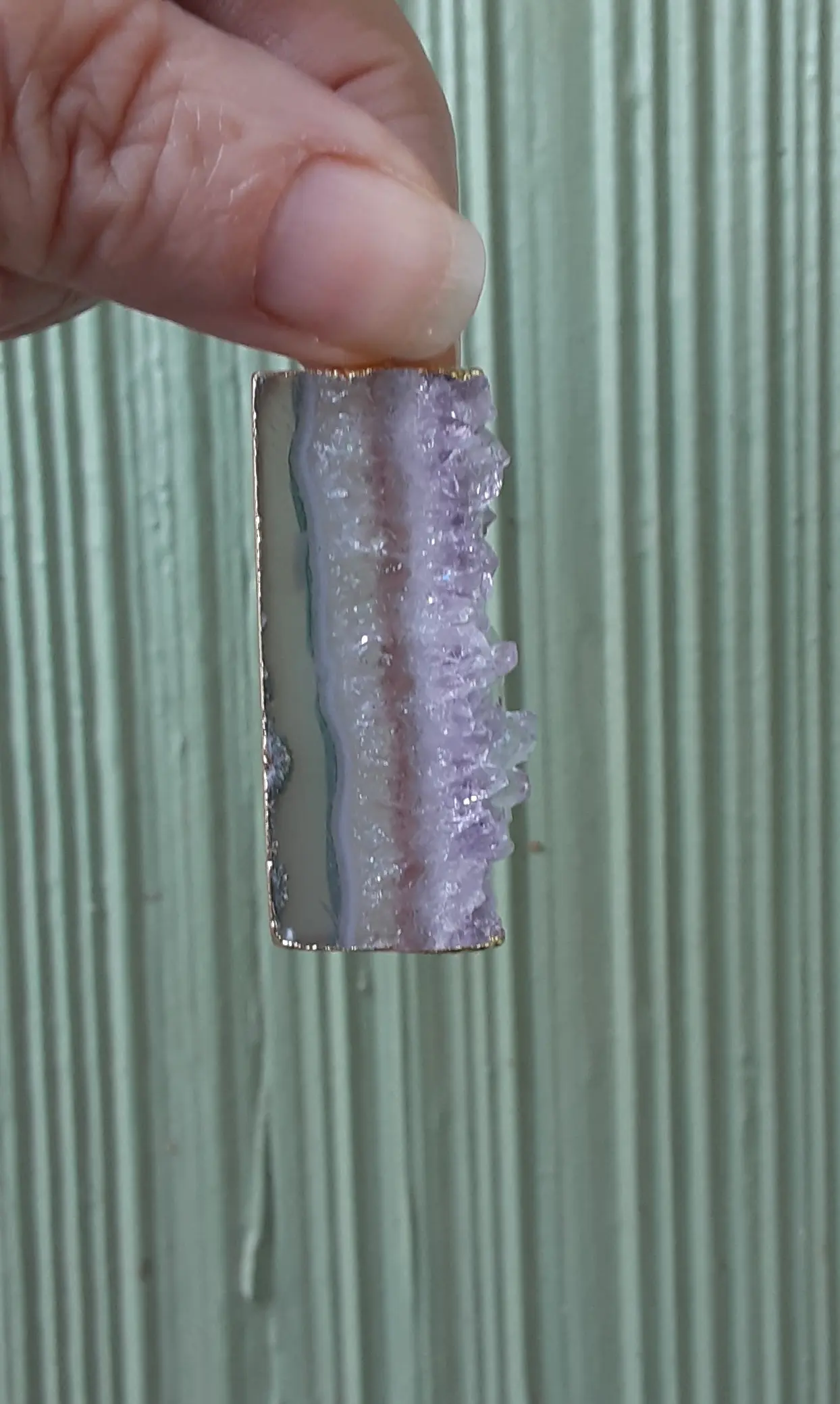 Hand holding a purple geode slice.